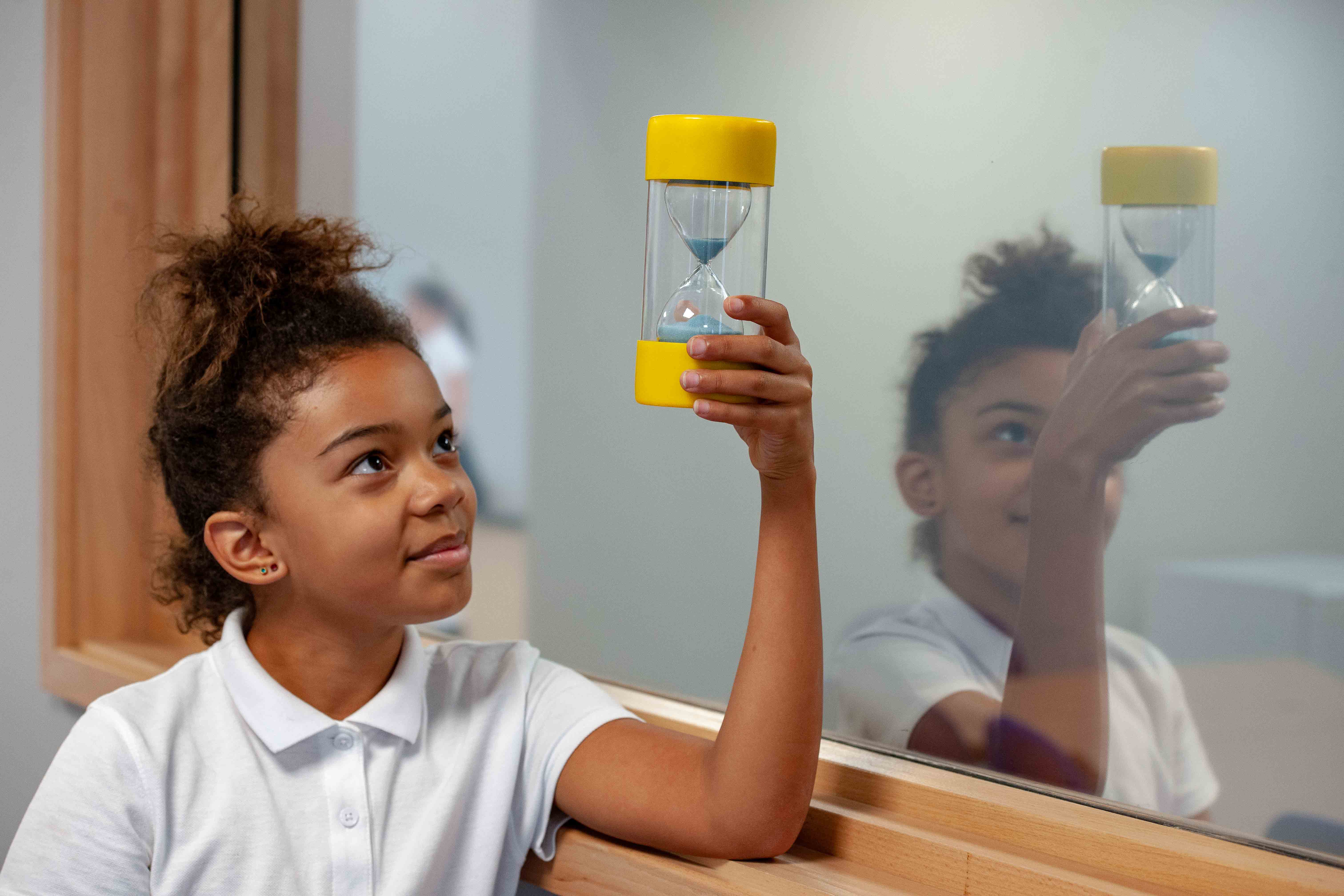 Young girl holding an egg timer.